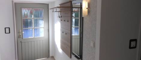 A hallway with a door, a coat rack, and a wall-mounted mirror.