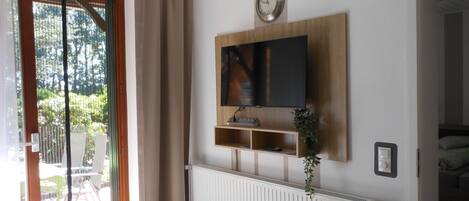 Una sala de estar moderna con un ventanal grande, puerta corrediza de vidrio y un televisor de pantalla plana montado en una pared de madera.