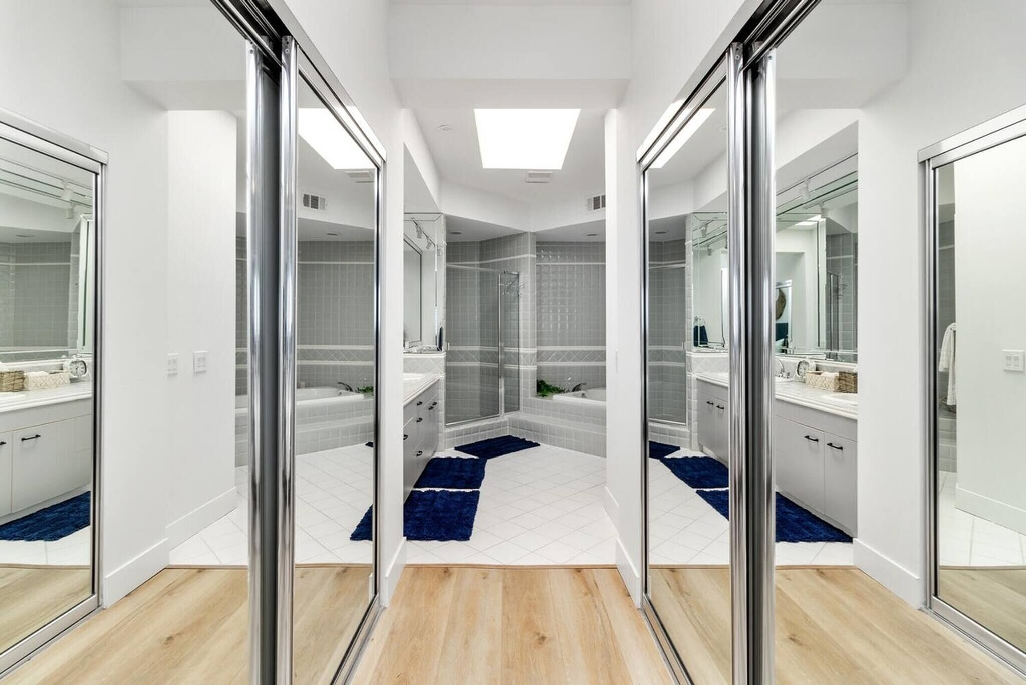 A modern bathroom with glass doors, a shower, and a large mirror.