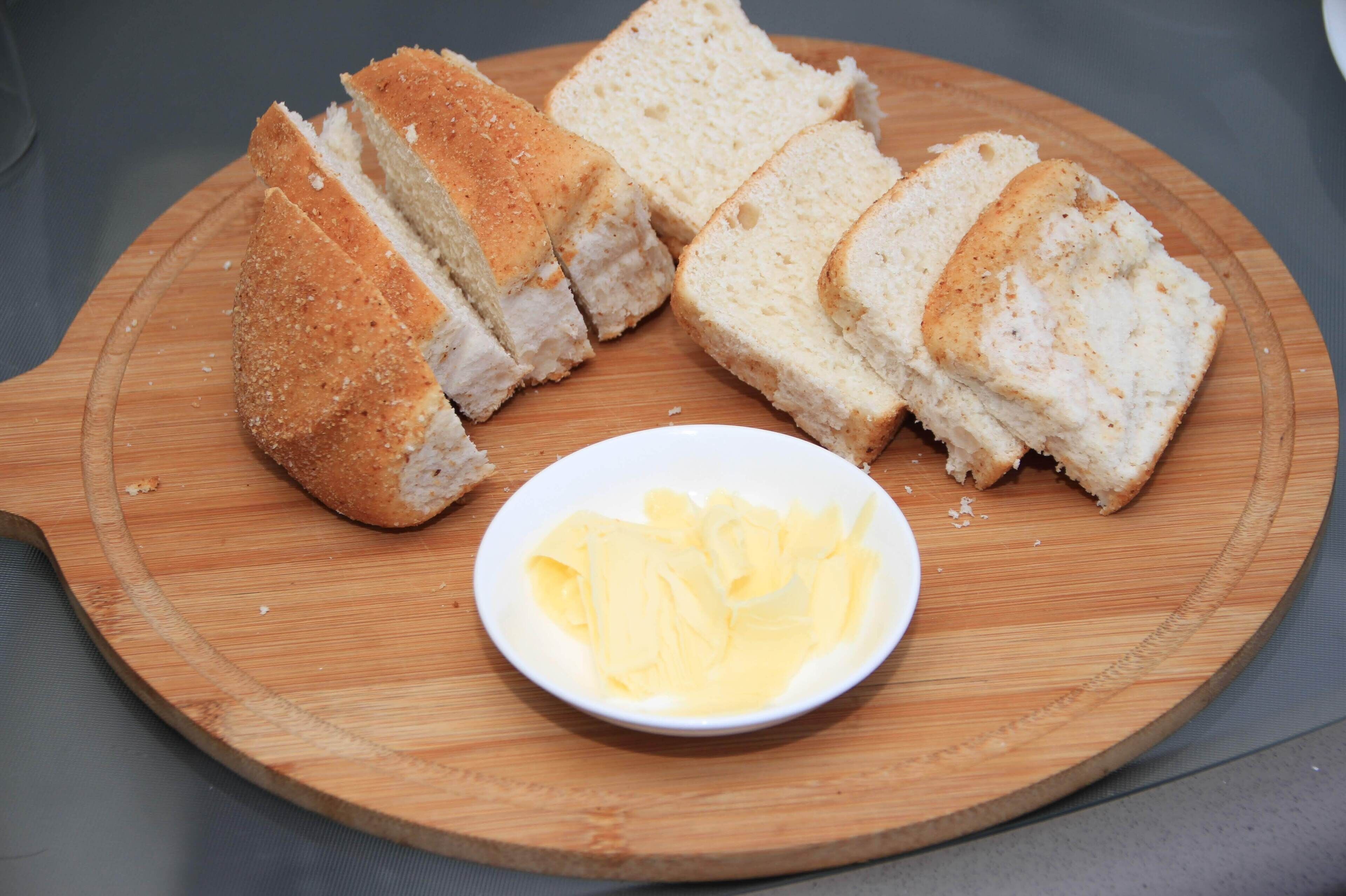 Brot auf einem Holzboden, dazu eine kleine Schale Butter.