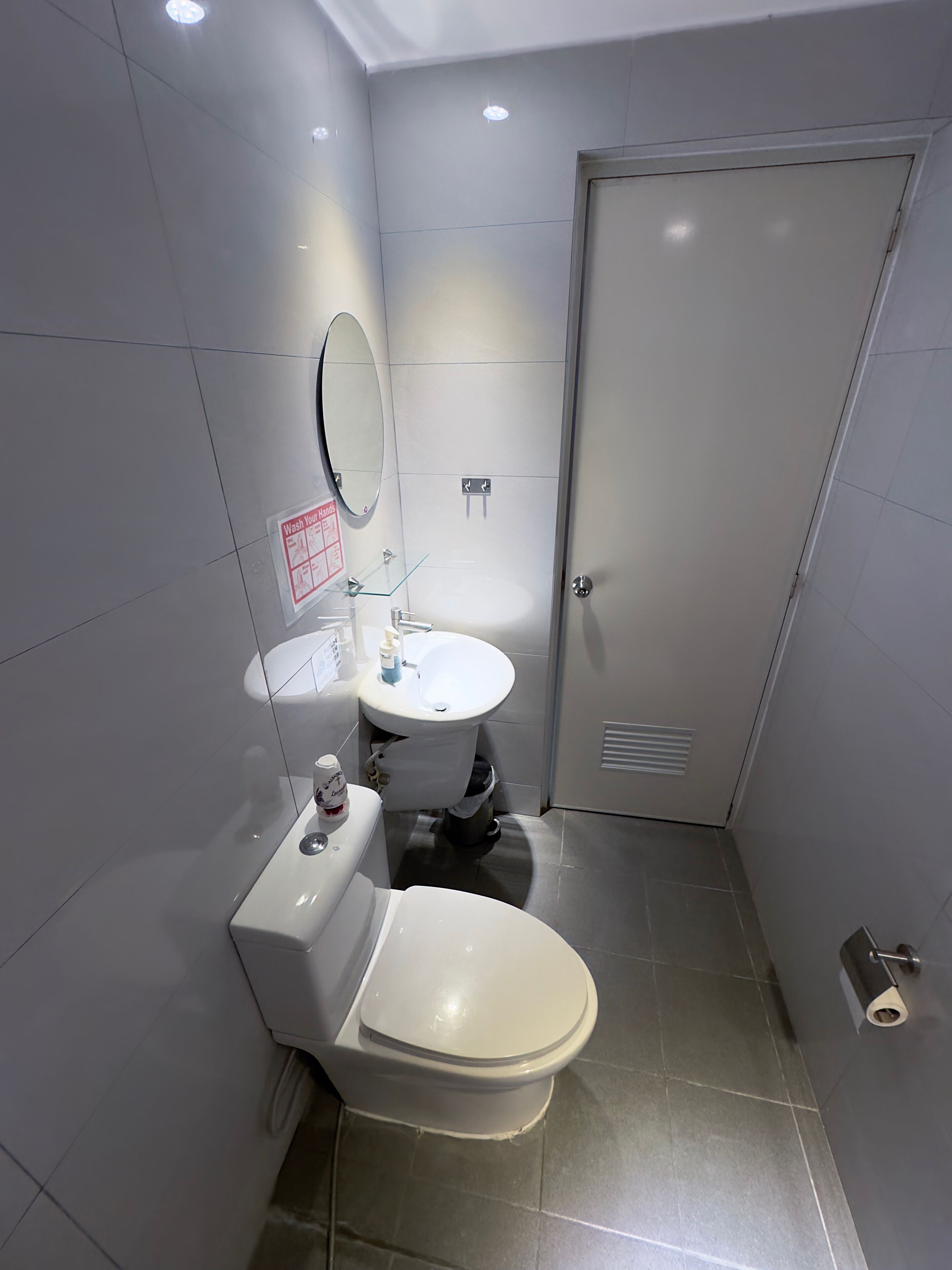 A modern bathroom with a toilet, sink, and mirror.