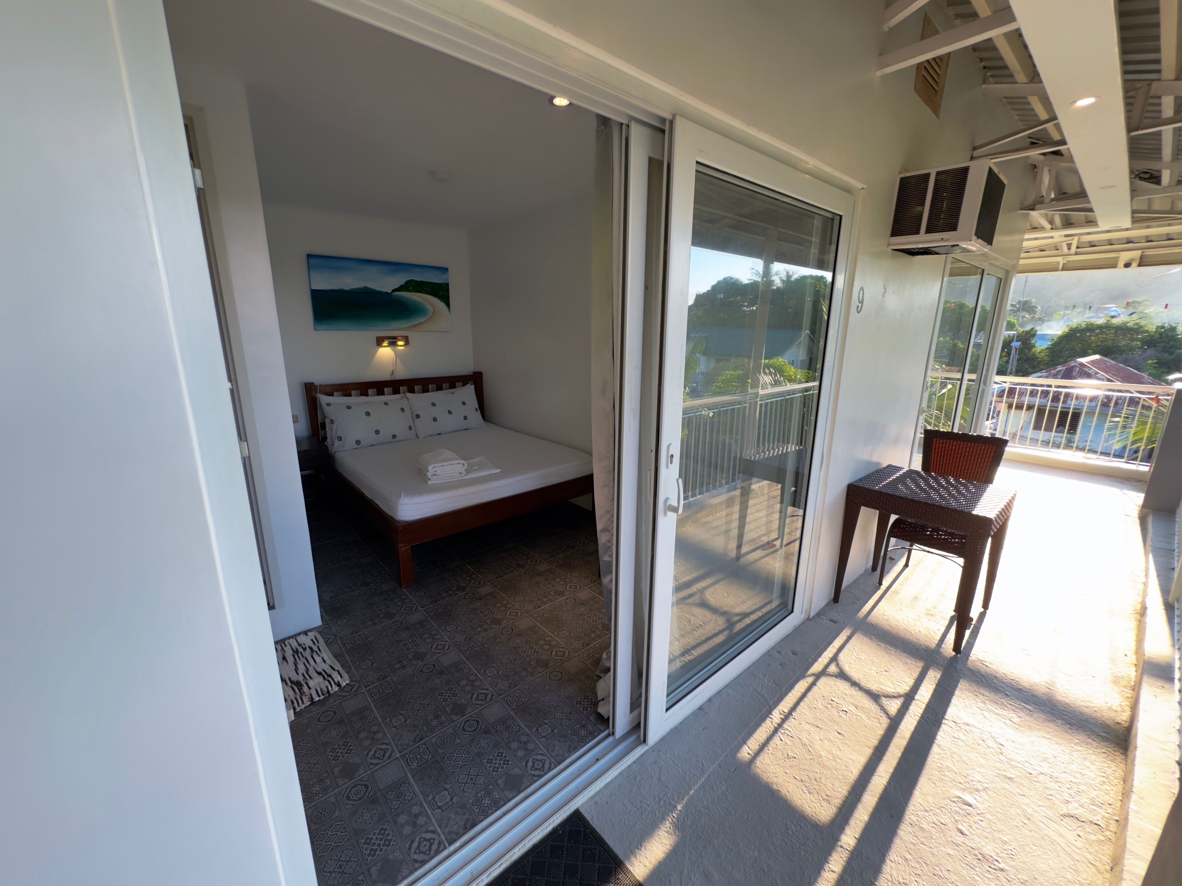 Ein Balkon mit einem Bett, einem Stuhl und Blick ins Freie.