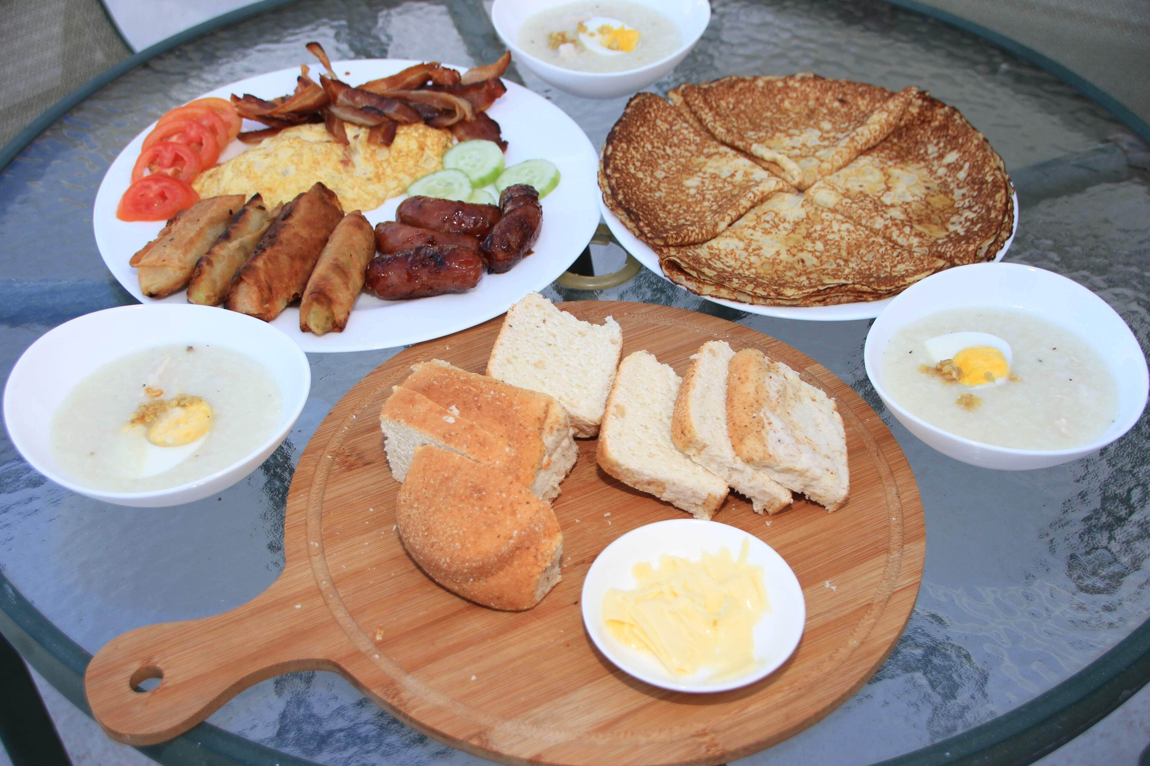 A breakfast table with various dishes including eggs, bacon, sausages, toast, and soup.