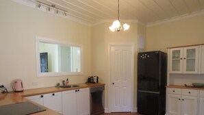 Eine Küche mit Holzarbeitsplatten, weißen Schränken, einem schwarzen Kühlschrank und einem Fenster über der Spüle.