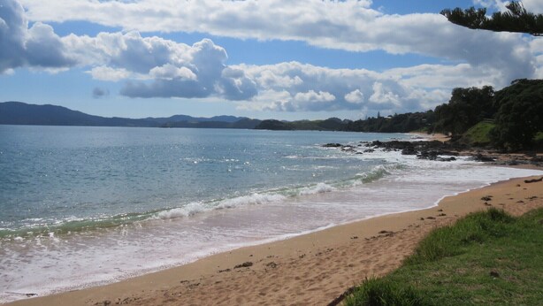 Ein Strand mit blauem Himmel und dem Schriftzug 'Cable Bay'.