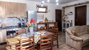 A cozy living room with a patterned sofa, a dining area with a wooden table and chairs, and a kitchen with wooden cabinets and a tiled backsplash. - A Place in the Sun - Caltanissetta (Caltanissetta)