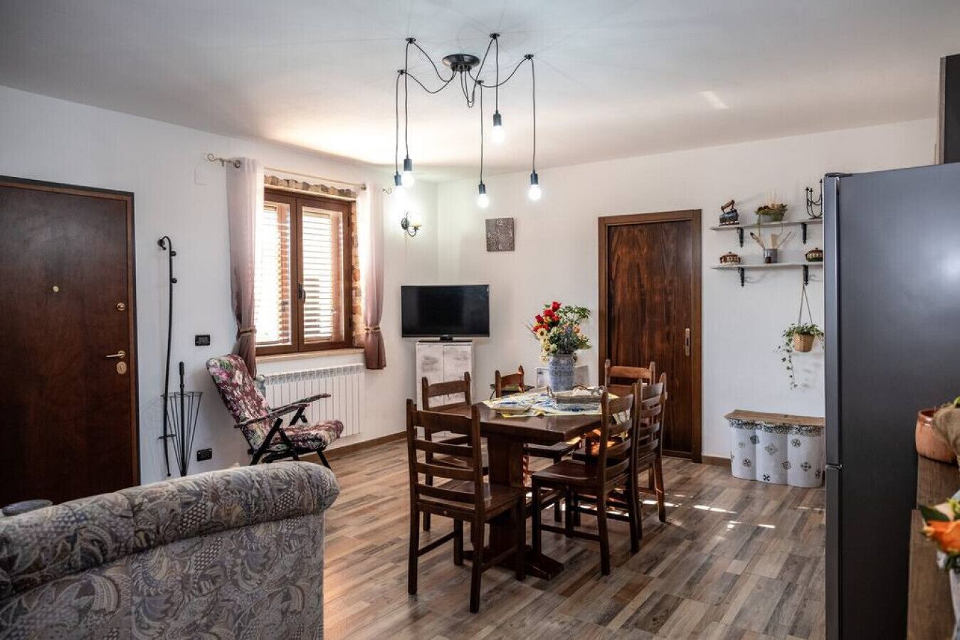 Un salon chaleureux avec un coin repas, un plancher en bois, un téléviseur et une cheminée.