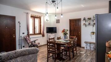 Un salon chaleureux avec un coin repas, un plancher en bois, un téléviseur et une cheminée.
