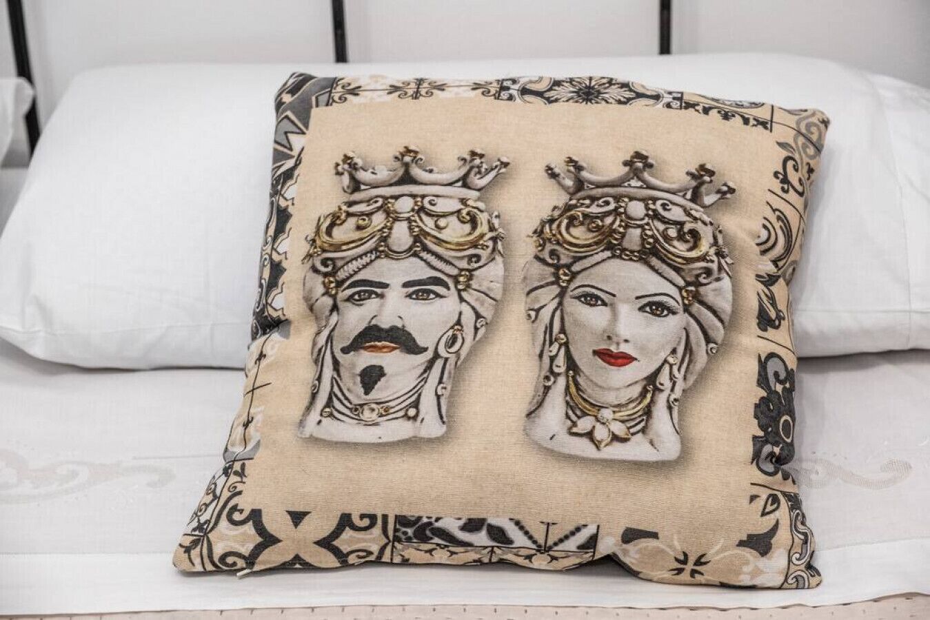 Una cama con un cojín decorativo que presenta dos diseños ornamentales.