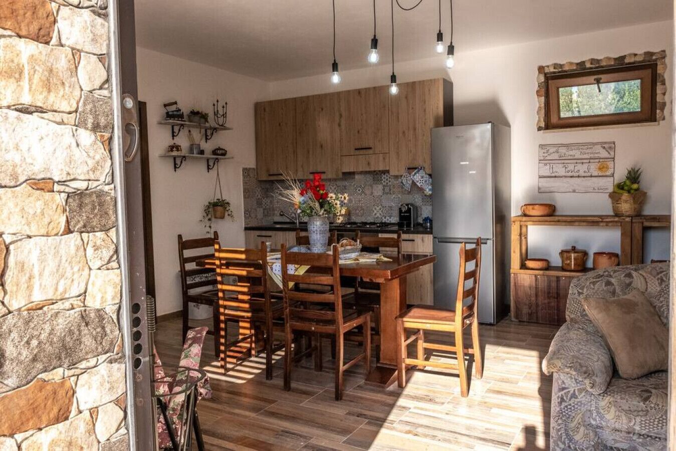 Une cuisine chaleureuse avec des meubles de rangement en bois, une table à manger avec des chaises et un réfrigérateur.