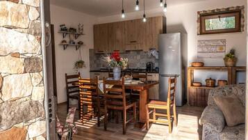 A cozy kitchen with wooden cabinets, a dining table with chairs, and a refrigerator.