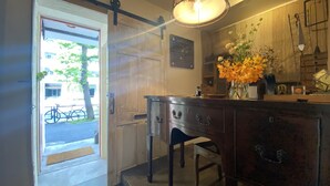A hotel room with a wooden dresser, a chair, a desk with a lamp, and a vase with flowers. - TOE LIBRARY (Tokyo)