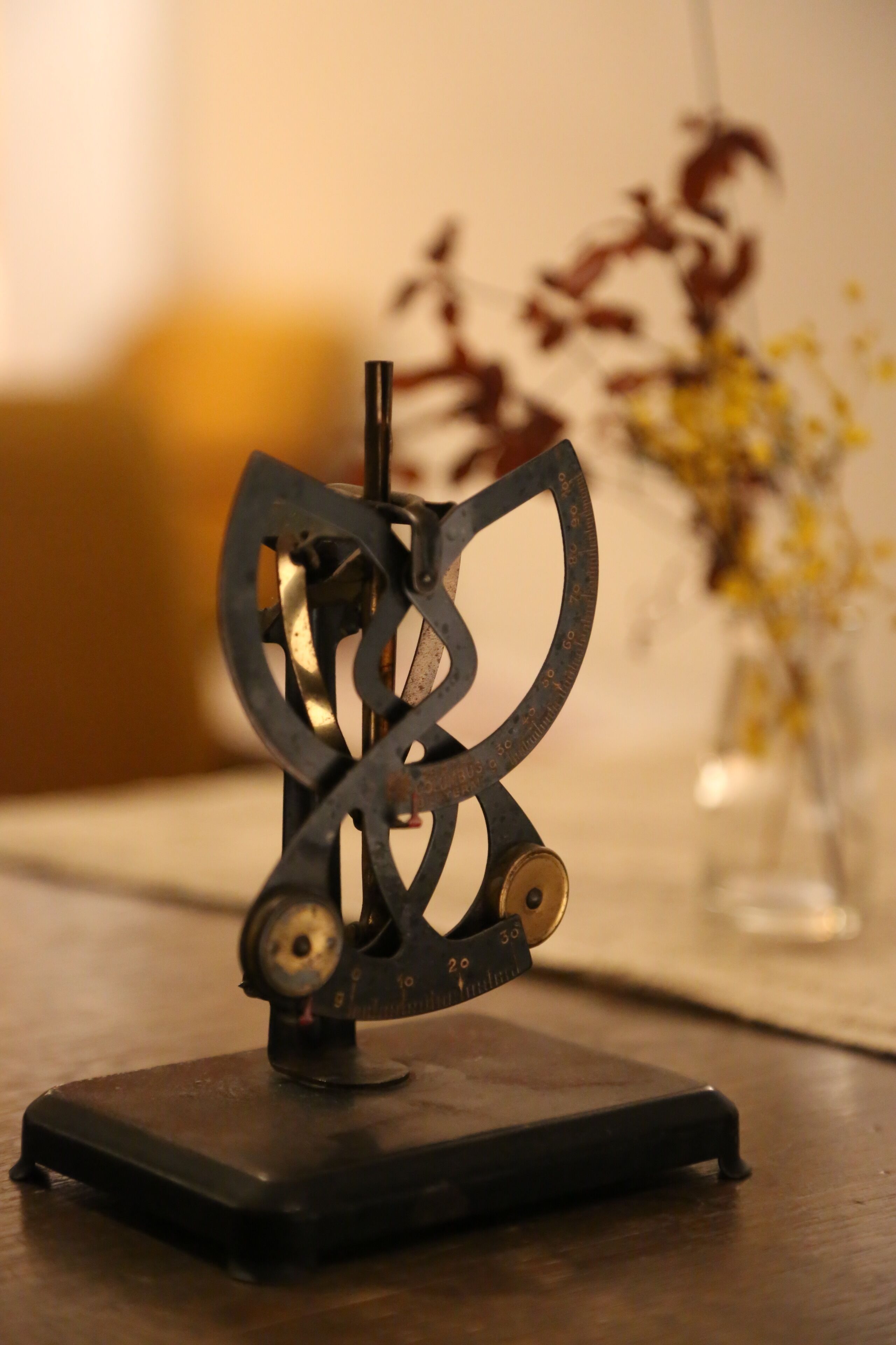 A metal sculpture with a circular base on a wooden surface.