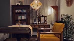A cozy room with a wooden desk, a yellow armchair, a bookshelf, and a decorative lamp. - TOE LIBRARY (Tokyo)