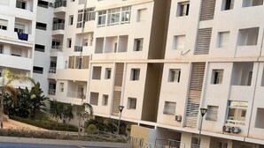 Una piscina con suelo de baldosas, rodeada por un edificio de varios pisos con balcones y unidades de aire acondicionado.