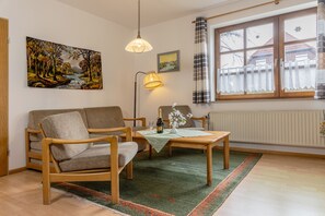 Uma sala de estar aconchegante, com um sofá, uma mesa de centro de madeira e um quadro de uma paisagem.