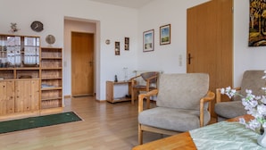 A living room with a wooden bookshelf, a wooden coffee table, and two armchairs. - Völlig Ausgeglichen: Die Erdgeschoss-wohnung Liegt in Unmittelbarer Nähe des Kur (Carolinensiel)
