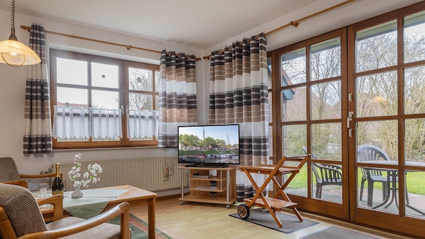 A cozy living room with a television, wooden furniture, and large windows. - Völlig Ausgeglichen: Die Erdgeschoss-wohnung Liegt in Unmittelbarer Nähe des Kur (Carolinensiel)