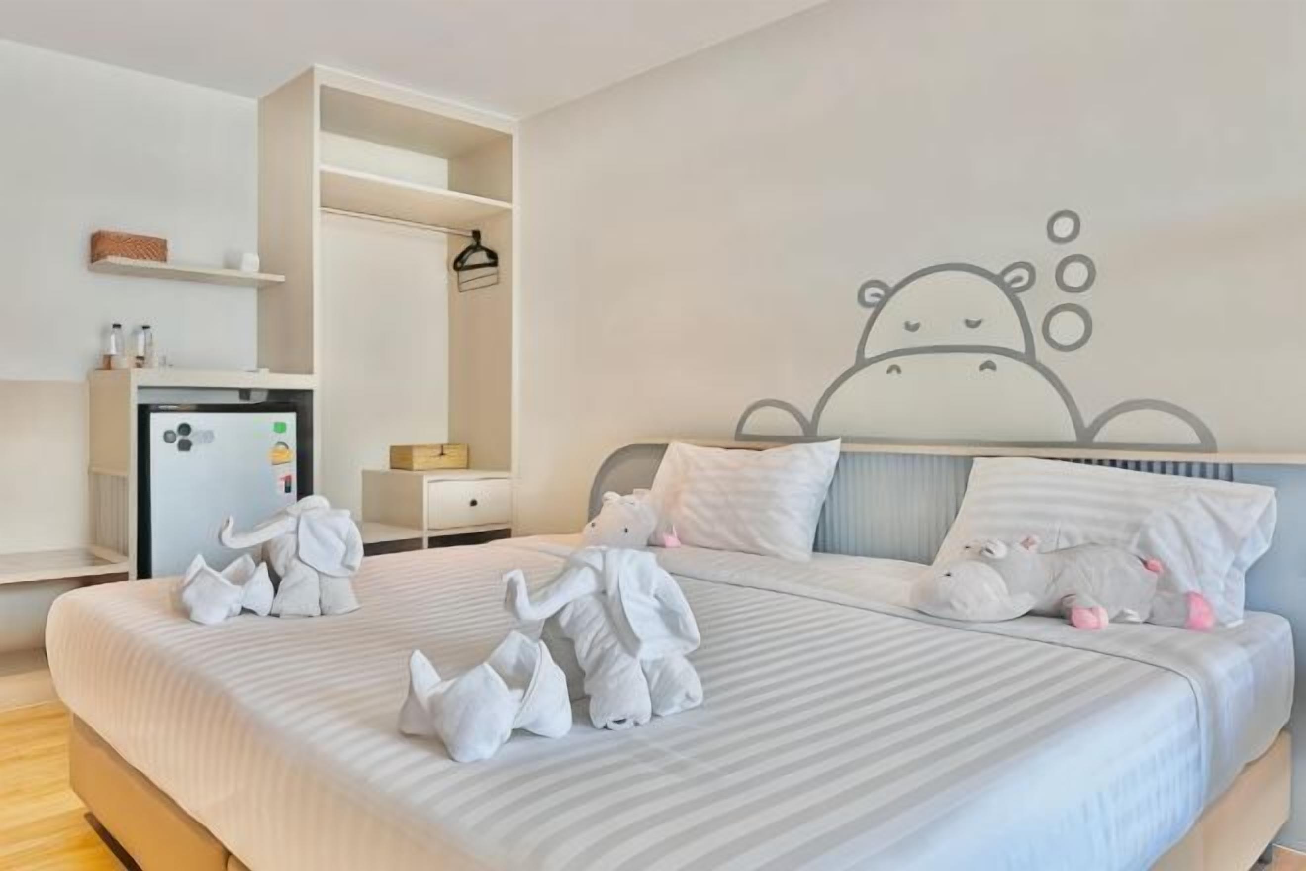 A hotel room with a bed, a wardrobe, a desk, and a wall decoration.