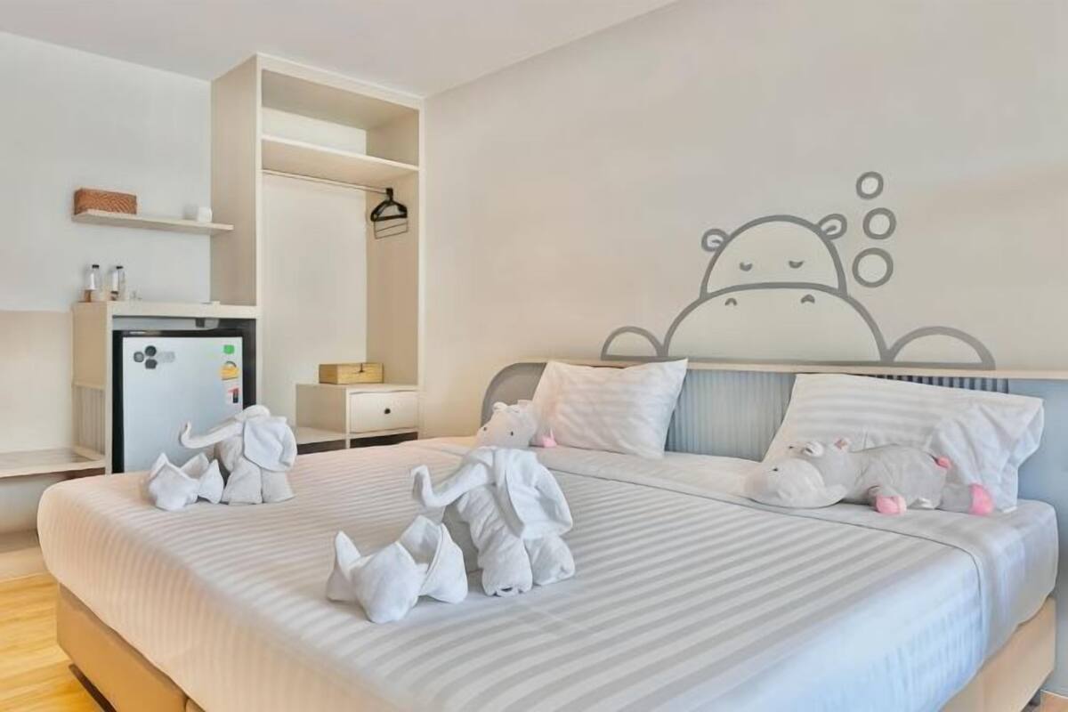 A hotel room with a bed, a wardrobe, a desk, and a wall decoration.