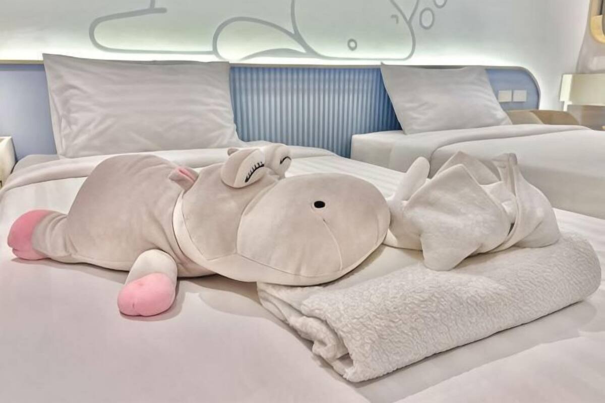 A bed with a plush toy, pillows, and a folded towel.