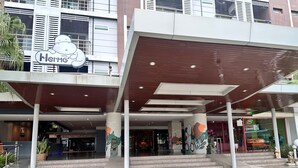A hotel entrance with a modern design, featuring a large overhang and steps leading up to the entrance. - Herma Hotel (Bang Phli)