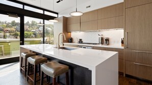 A modern kitchen with a large island, bar stools, and a view of a residential area.