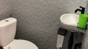 Une salle de bain équipée de toilettes, d’un lavabo et d’un porte-rouleau de papier toilette.