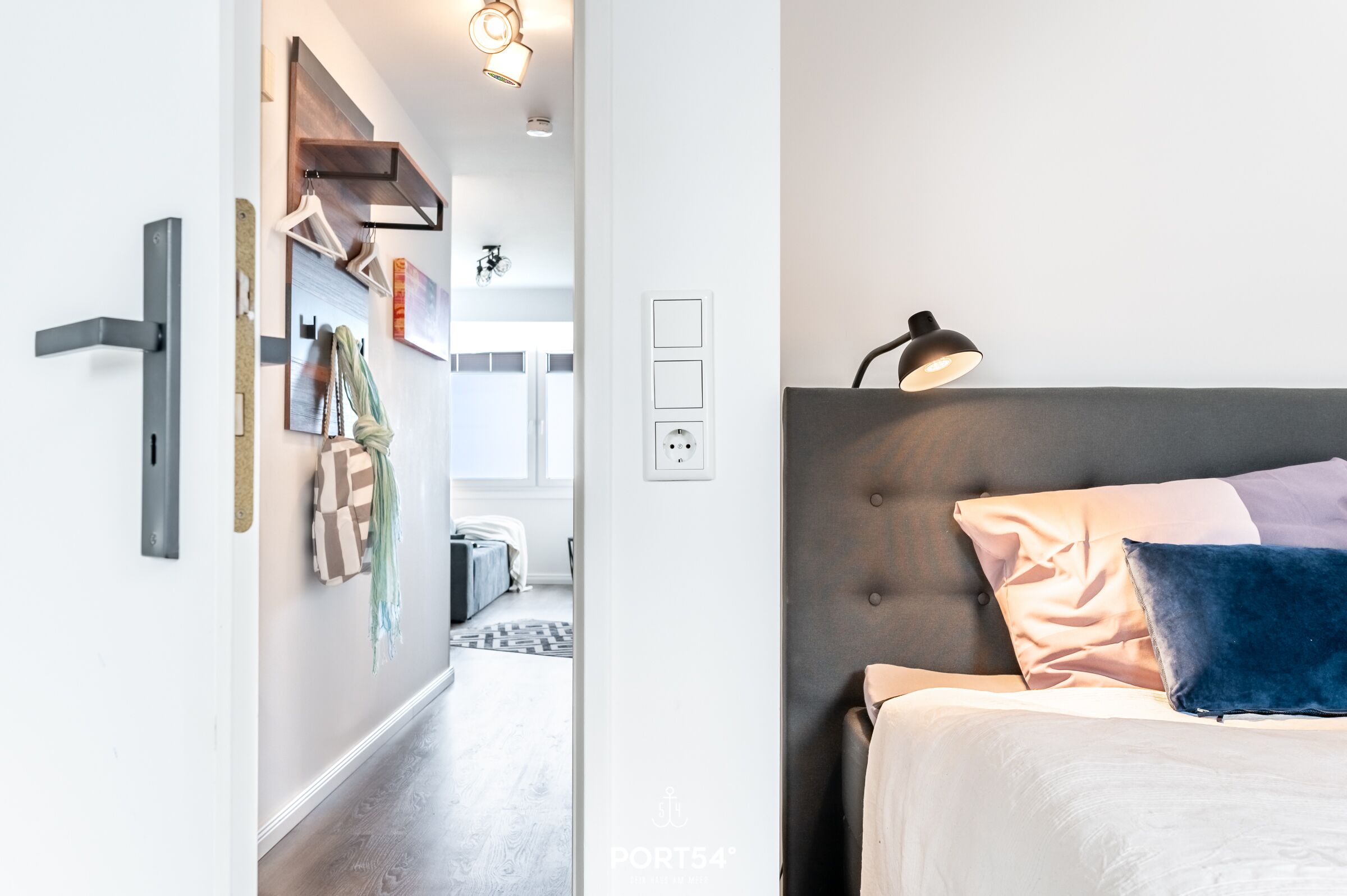 Ein modernes Schlafzimmer mit grauem gepolsterten Kopfteil, einer Nachttischlampe und zwei Kissen.