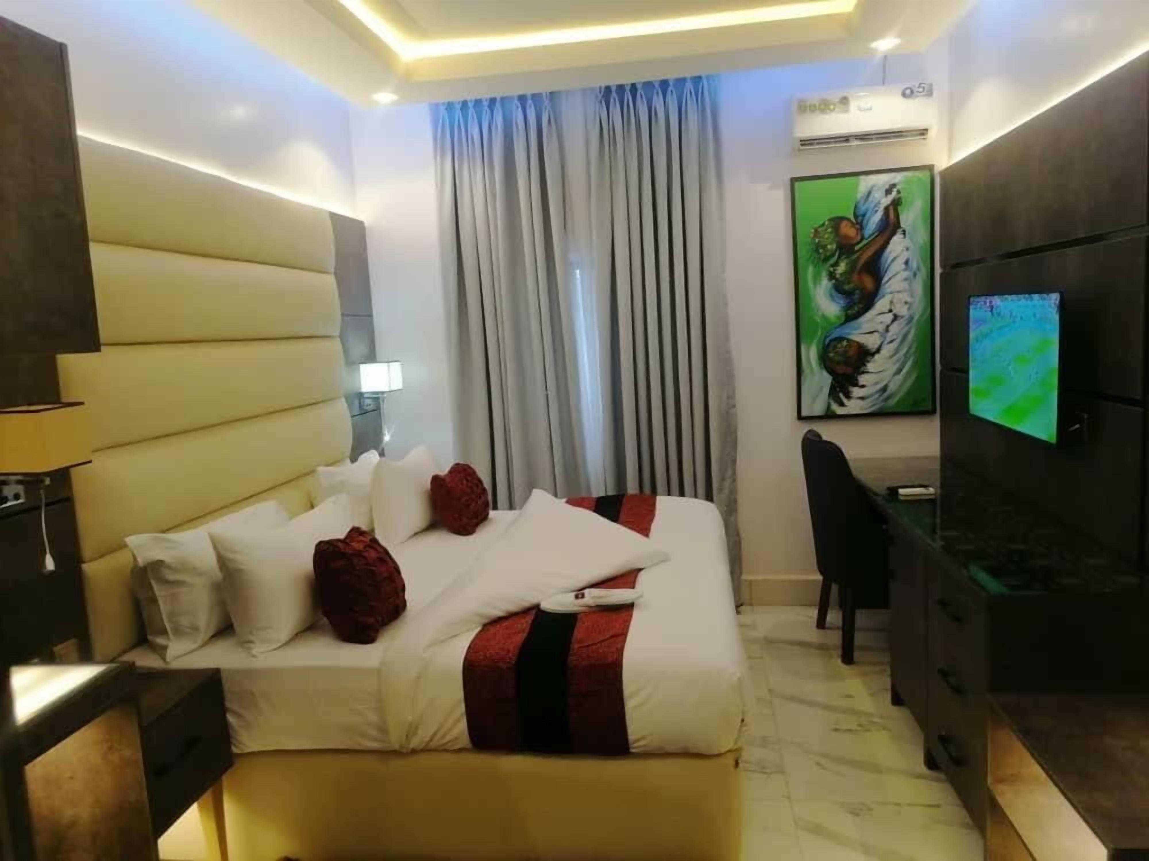 Ein modernes Hotelzimmer mit einem großen Bett, einem Schreibtisch, einem Sessel und einem Fernseher.
