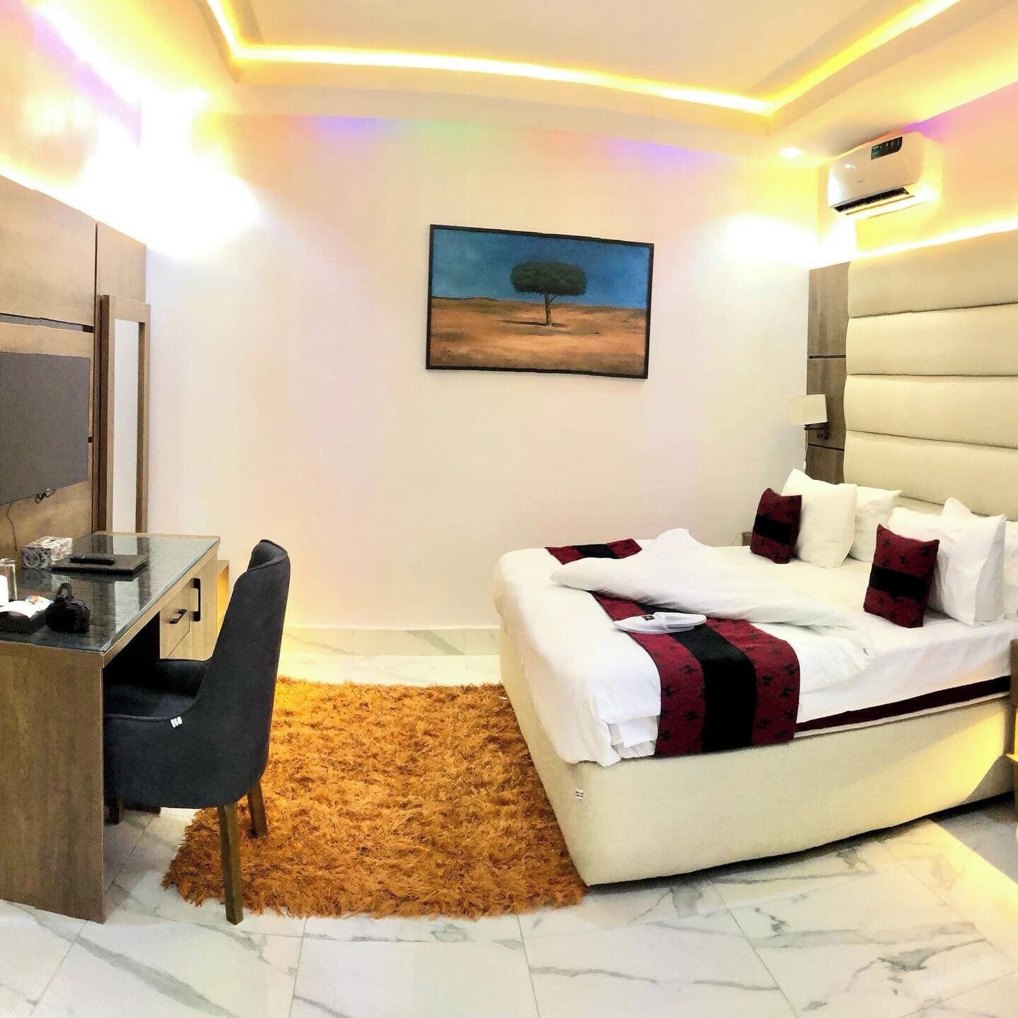 A modern hotel room with a bed, a desk, and a chair.