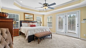 A bedroom with a bed, a bench, a dresser, a mirror, and a ceiling fan.