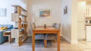 Un coin repas avec une table et des chaises en bois, une bibliothèque et un tableau accroché au mur.