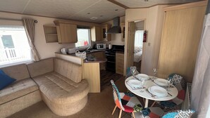 A compact RV kitchen with a dining area, a kitchenette, and a seating area. - Burgh Castle 3-Bed Haven: Near Norfolk Broads (Burgh Castle)