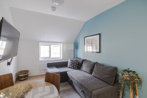 Relax in this spacious living room with a flat-screen TV, comfortable sofa, and large window offering a view.