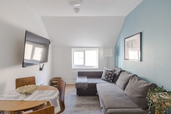 Relax in a spacious living area with a large flat-screen TV, comfortable sofa, and decorative table.