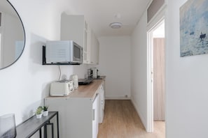 Kitchen features a microwave, toaster, and potted plant, with a door leading to another room.