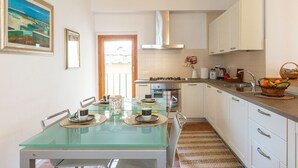 A modern kitchen with a glass dining table, white cabinets, and a stainless steel range hood.