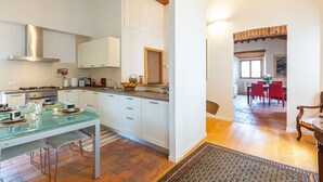 A modern kitchen with white cabinetry, a glass dining table, and a wooden floor.