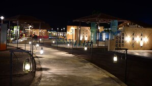 An outdoor area with tables and chairs under a covered structure, illuminated by lanterns. - Chokar Dhani Raipur (Raipur)
