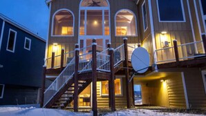 A two-story building with a balcony, a staircase, and a satellite dish. - Glacier + Tide Retreat (Homer)