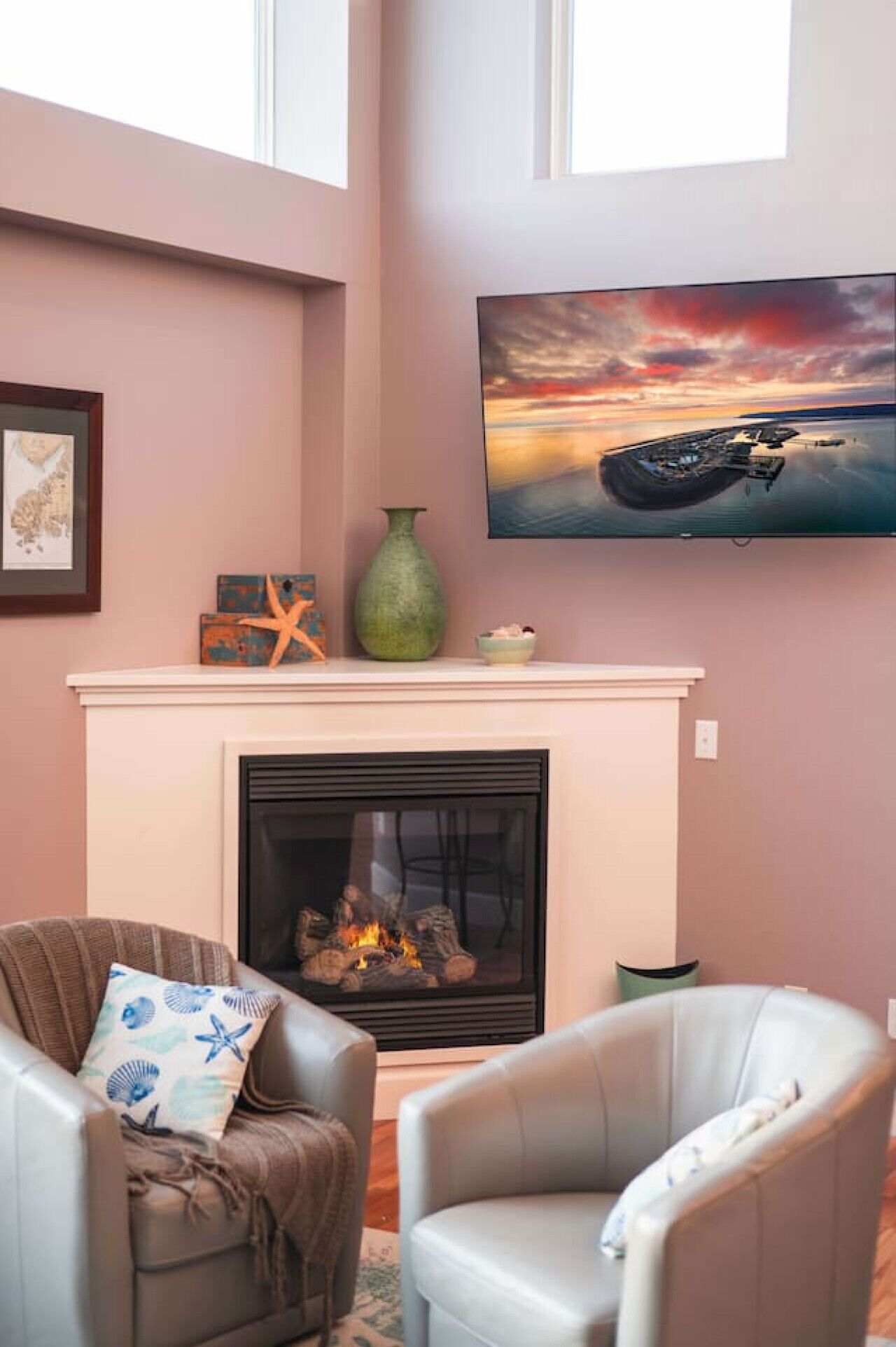 Ein Wohnzimmer mit Kamin, zwei Sesseln, einem Fernseher über dem Kamin und einem Bild an der Wand.