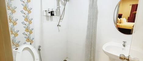 A small bathroom with a toilet, shower, and sink.