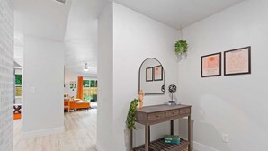 Ein modernes Interieur mit einem Holzkonsolentisch, einer hängenden Pflanze und gerahmten Kunstwerken an der Wand.