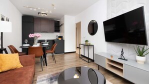 Een moderne woonkamer met een bank, salontafel en een aan de muur bevestigde televisie.