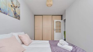 Un dormitorio con cama, almohadas, una manta, una toalla, un armario y una puerta.