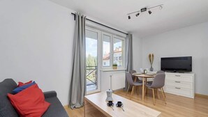 Una sala de estar moderna con sofá, mesa de centro, comedor y televisor.
