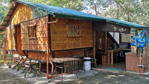 A rustic wooden cabin with a green roof, a small porch, and a table and chairs outside. - Isla Del Antoño (Cavinti)