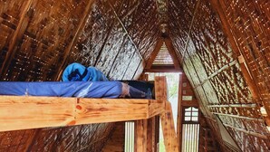 A cozy attic room with a wooden bunk bed, a fan, and a woven basket on the floor. - Isla Del Antoño (Cavinti)