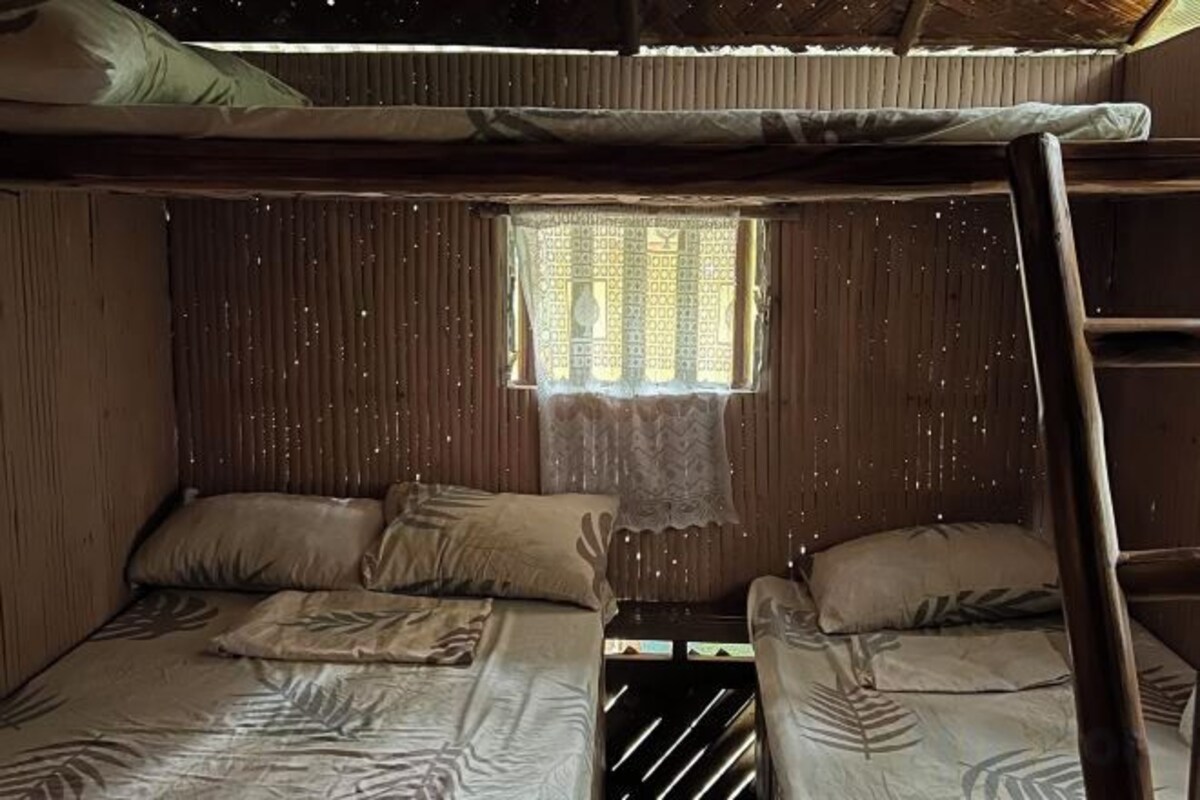A bunk bed room with a window, a ladder, and a small table.